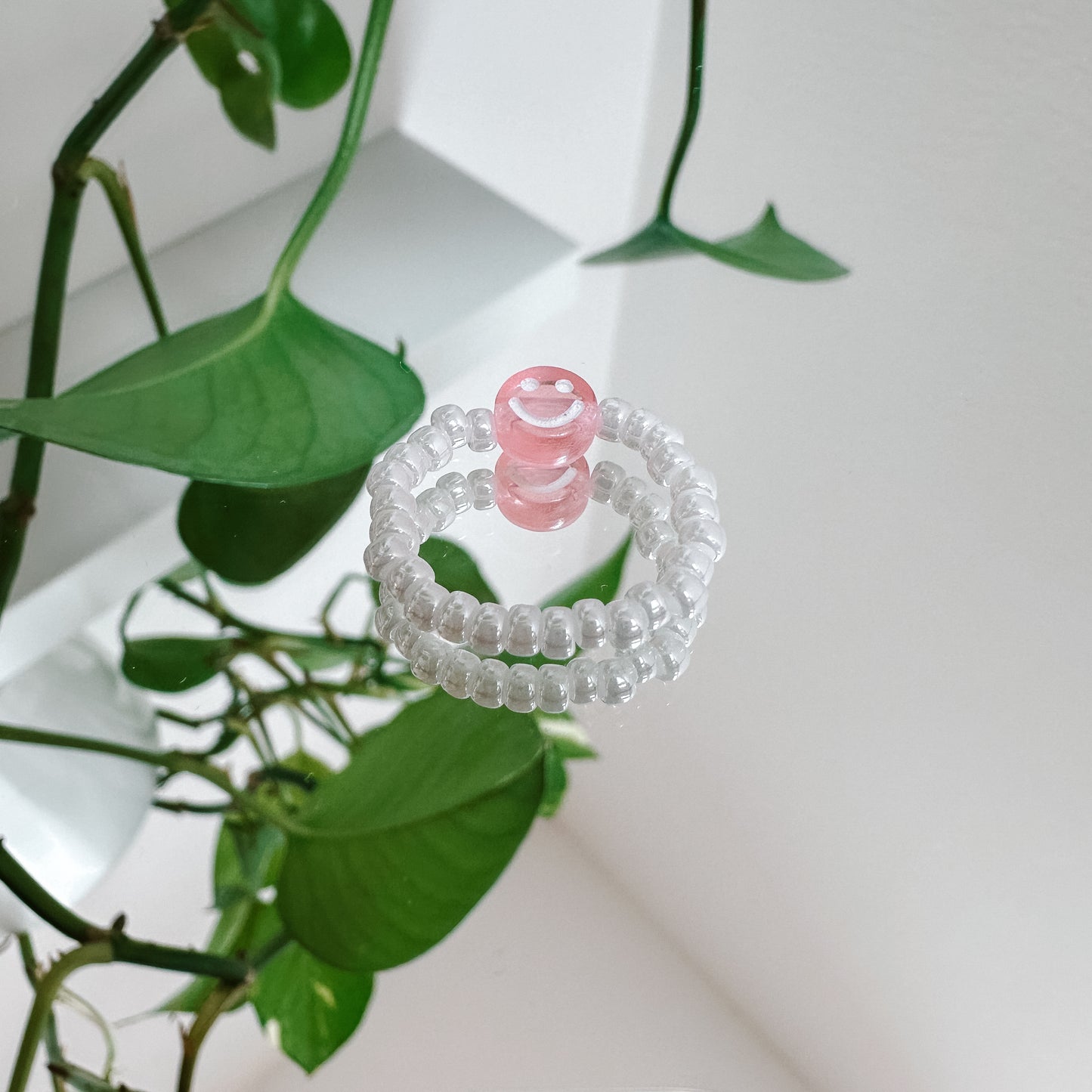 Perlenring aus weißen Glasperlen mit Smiley in Rosa