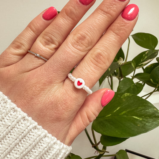 Perlenring aus weißen Glasperlen mit Herz in Rot