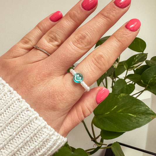 Perlenring aus weißen Glasperlen mit Smiley in Blau