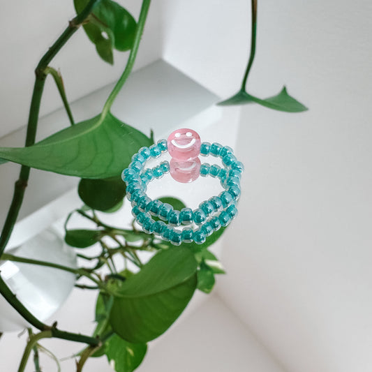 Perlenring aus Glasperlen in Aqua mit Smiley in Rosa