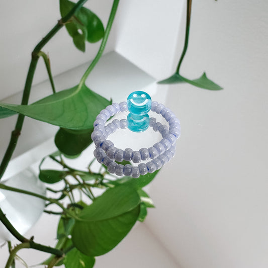 Perlenring aus Glasperlen in Flieder mit Smiley in Blau