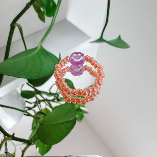Perlenring aus Glasperlen in Apricot mit Smiley in Lila