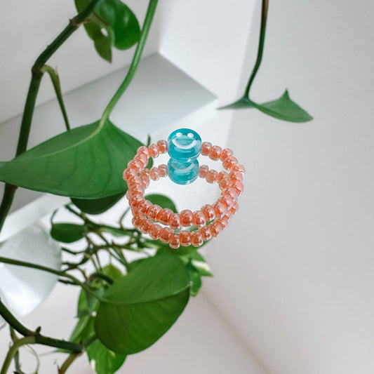Perlenring aus Glasperlen in Apricot mit Smiley in Blau