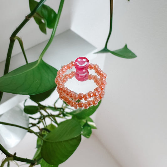 Perlenring aus Glasperlen in Apricot mit Smiley in Pink