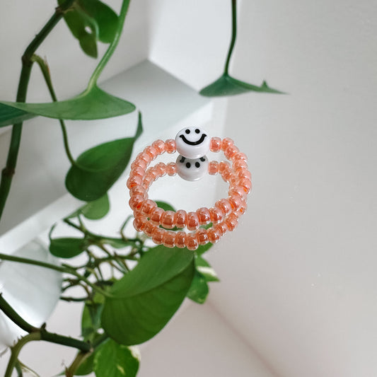 Perlenring aus Glasperlen in Apricot mit Smiley in Weiß