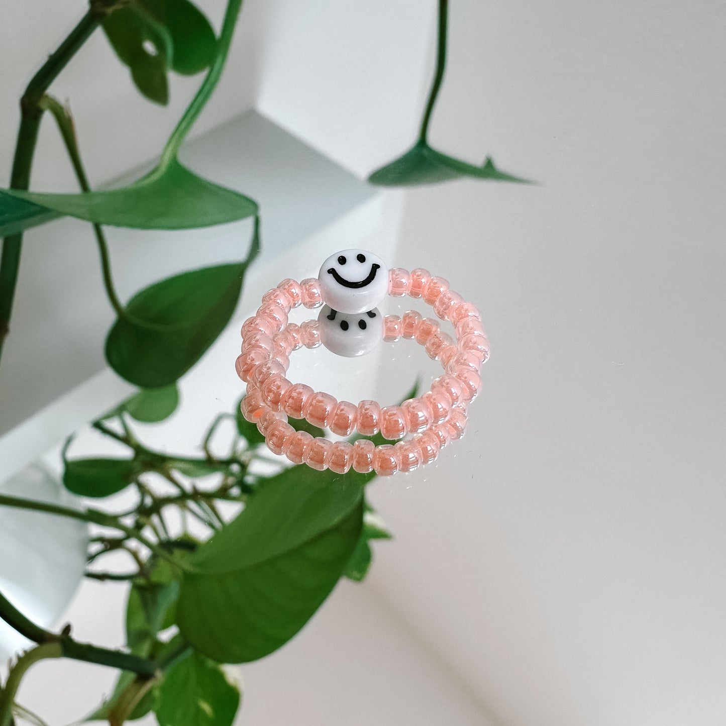 Perlenring aus Glasperlen in Pfirsich mit Smiley in Weiß