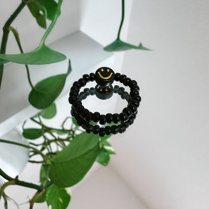 Perlenring aus schwarzen Perlen mit Smiley in Schwarz-Gold