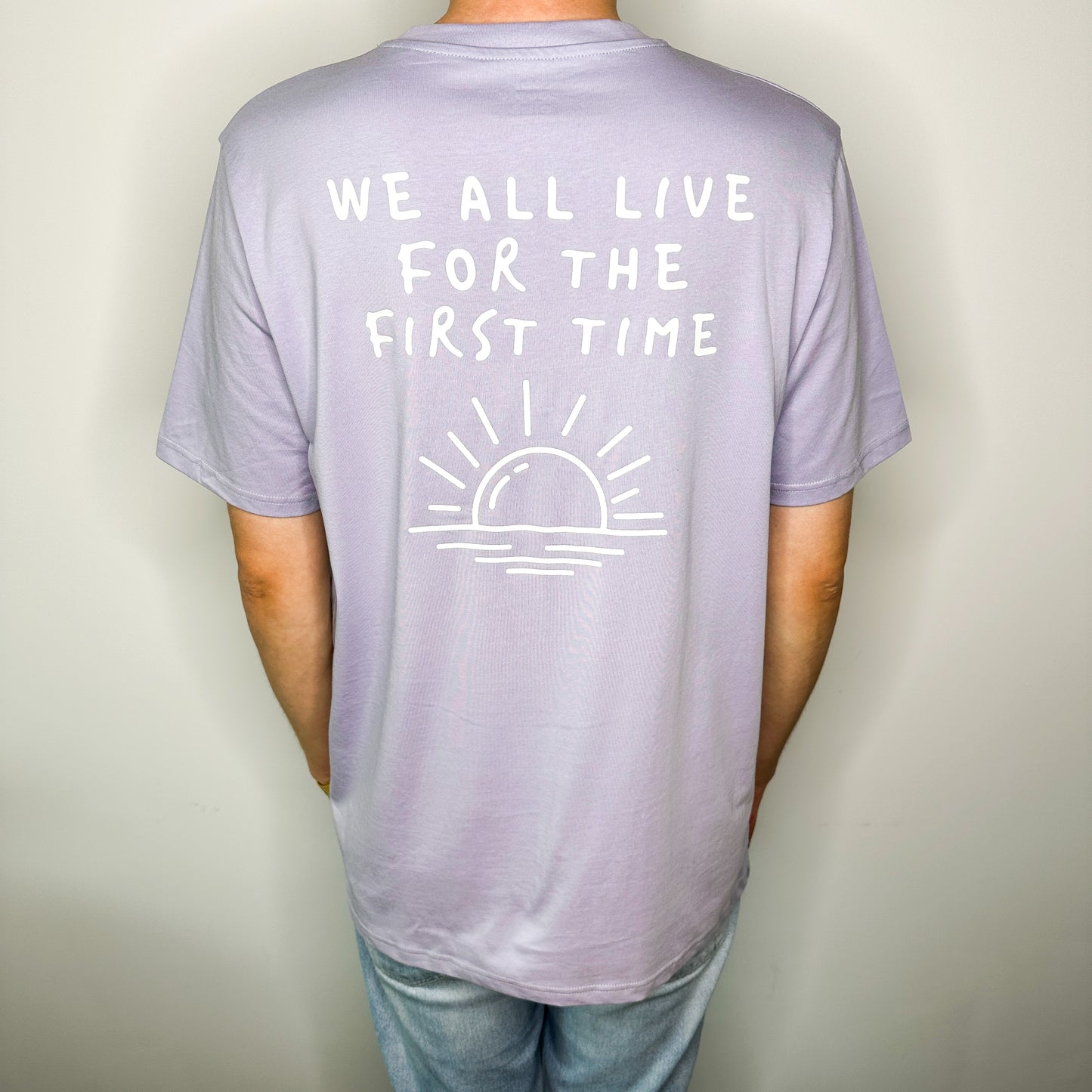 Unisex T-Shirt in Flieder mit Backprint „We all live for the first time“